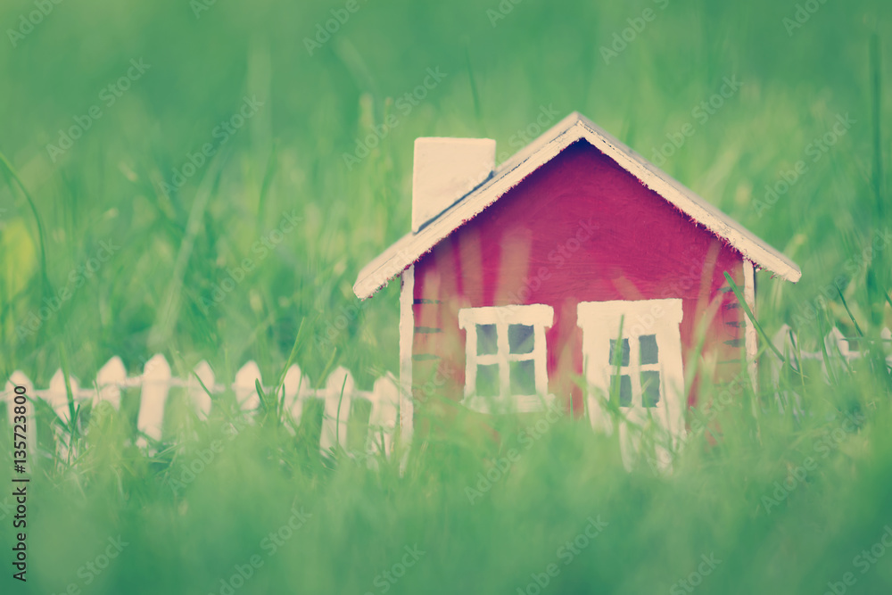 red wooden house model on the grass in garden