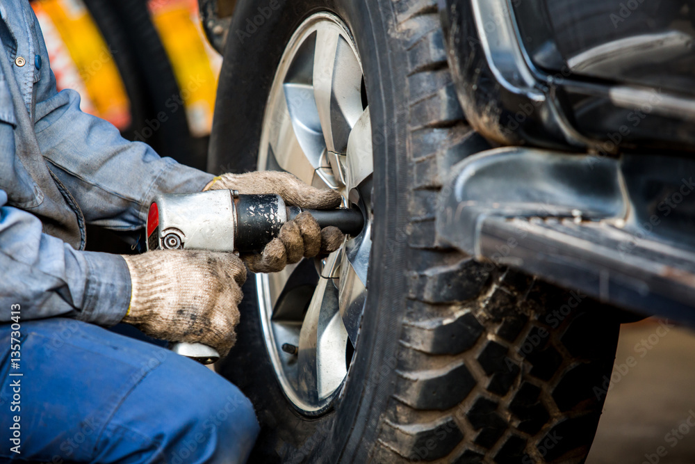 Mechanician changing car wheel in auto repair shop