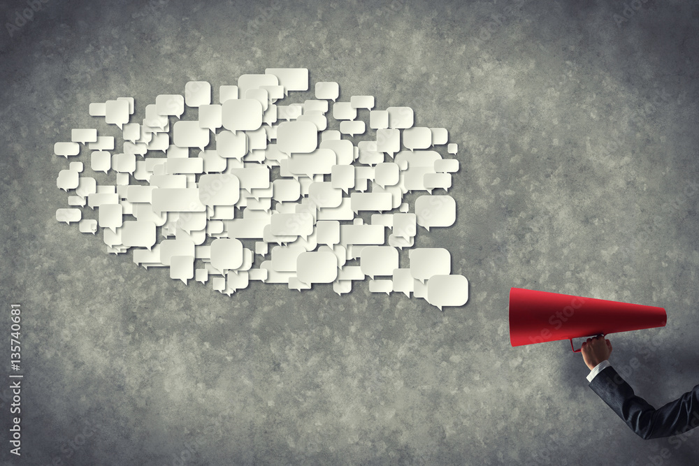 Hand of businesswoman holding red paper trumpet and speech cloud coming out