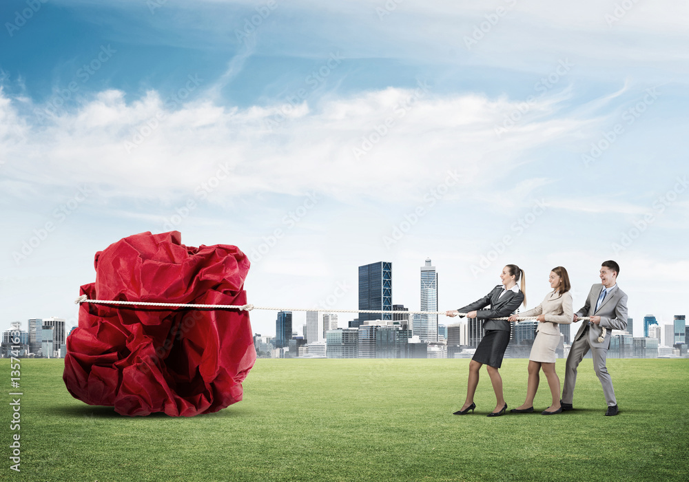 Young business people outdoors and huge paper ball as symbol of creativity