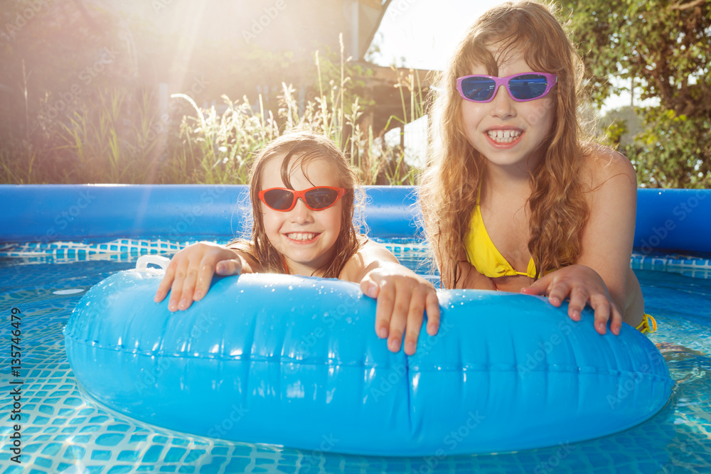 Smiling girls swimming in pool with  rubber ring