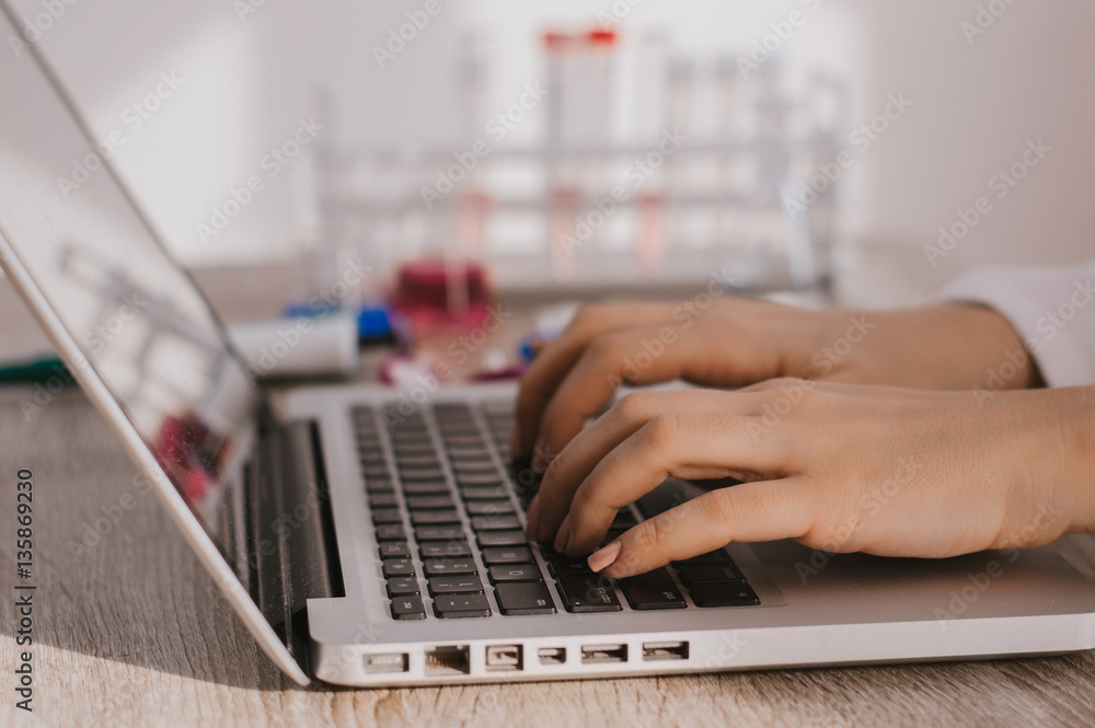 Medical researcher typing on keyboard in the labaratory writing