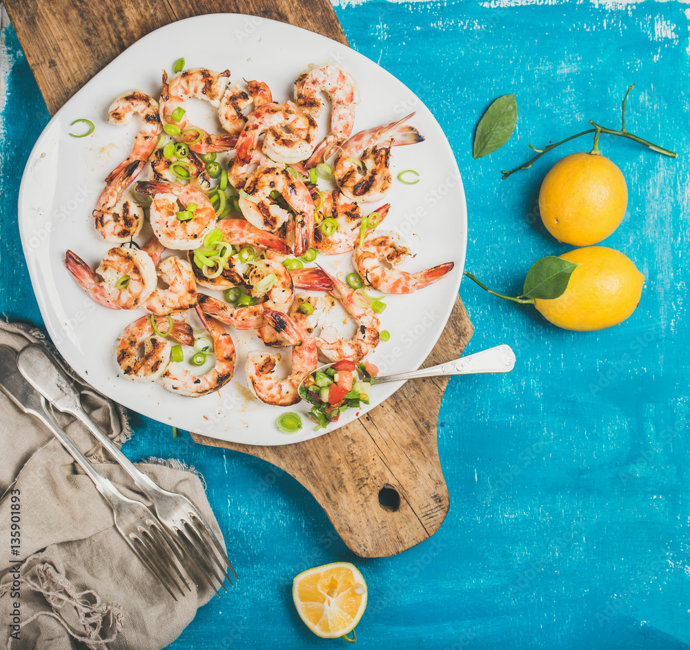 Seafood dinner. Grilled tiger prawns in white plate with lemon, leek and chili pepper on wooden boar