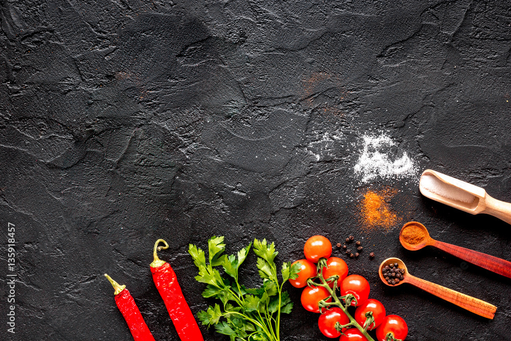 spices in wooden spoon on dark background top view