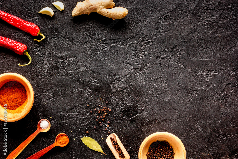 spices in wooden spoon on dark background top view