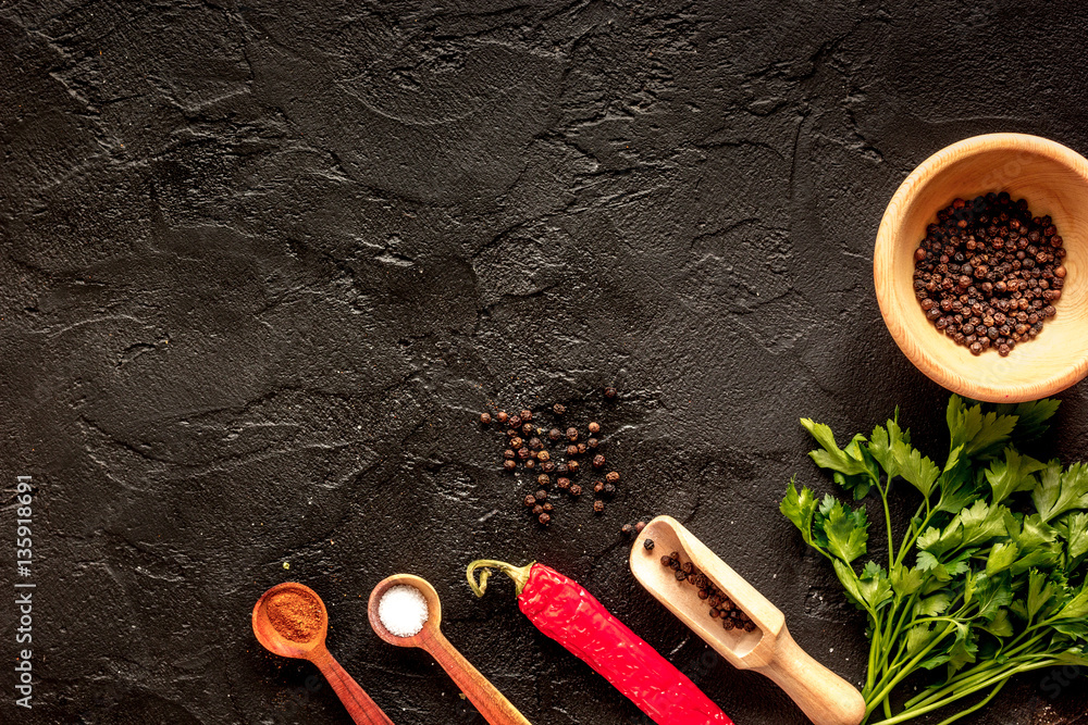 spices in wooden spoon on dark background top view