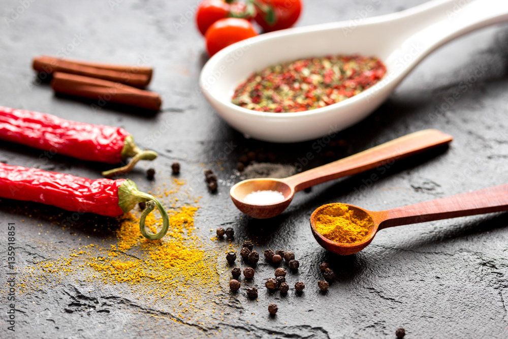 spices in wooden spoon on dark background