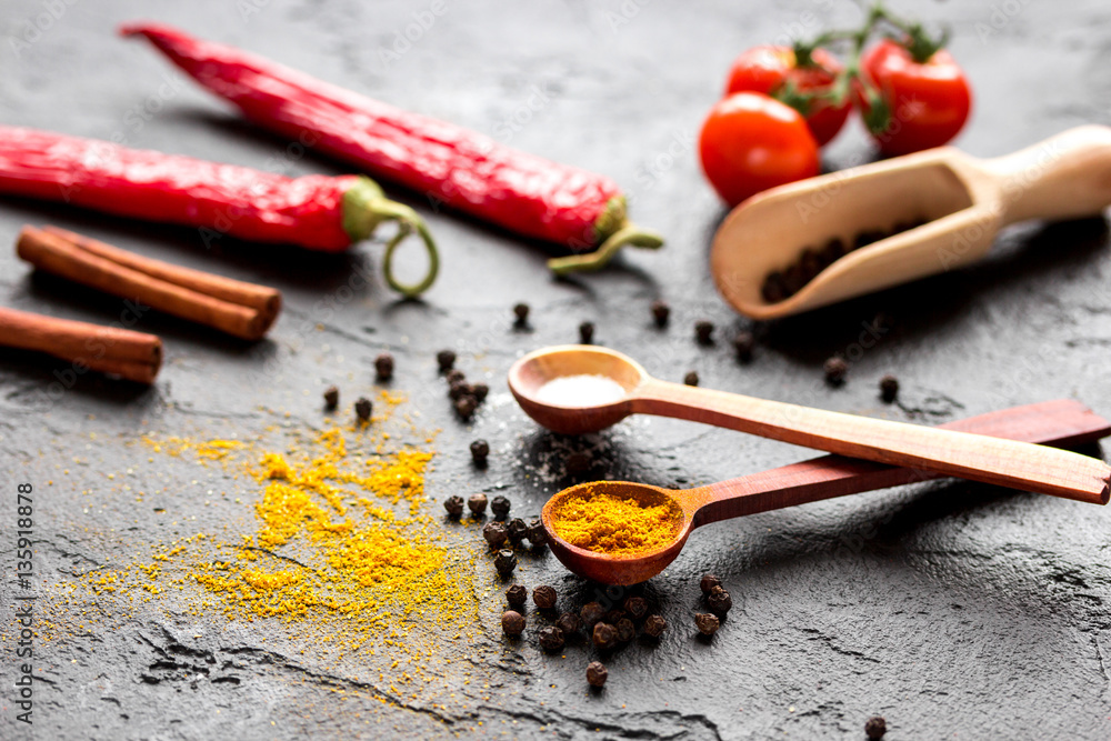 spices in wooden spoon on dark background