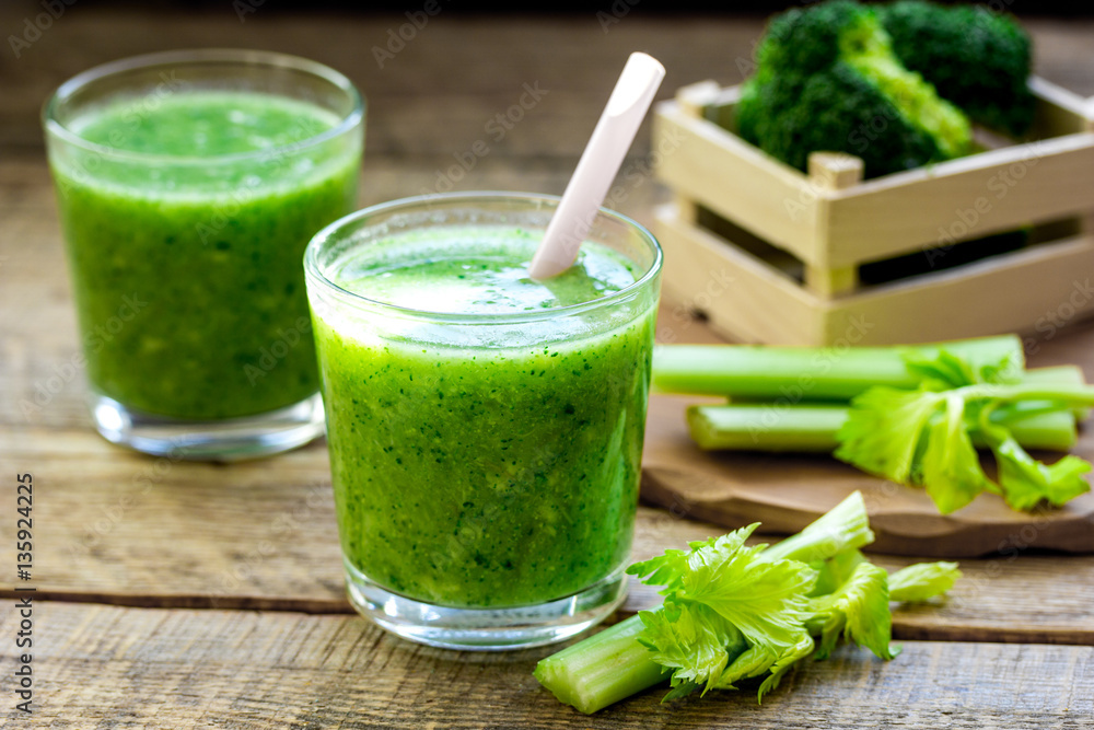 Green vegetable smoothie in glass at wooden background