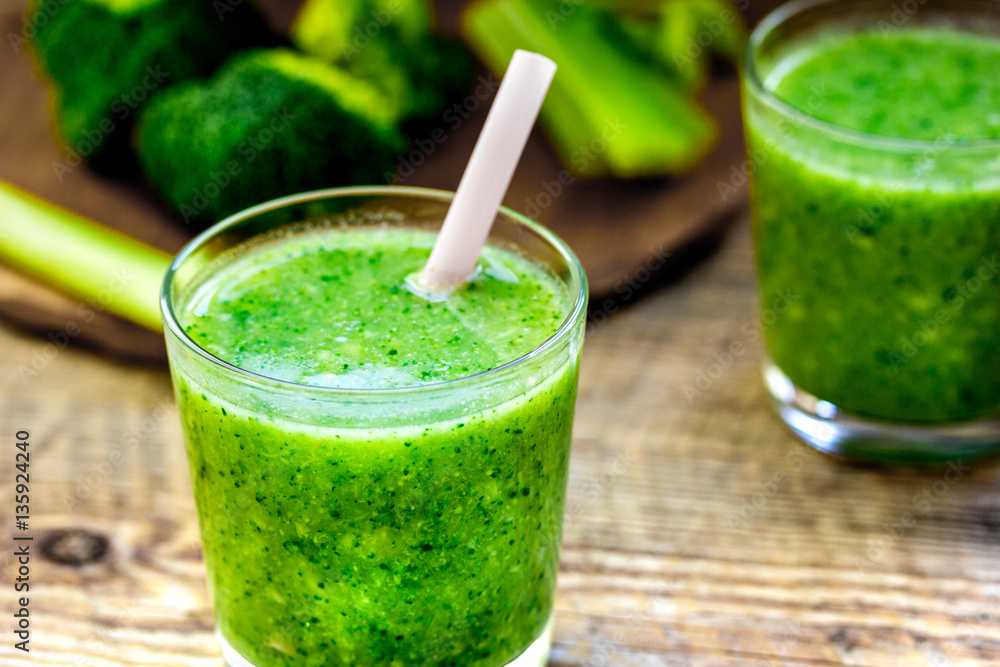 Green vegetable smoothie in glass at wooden background