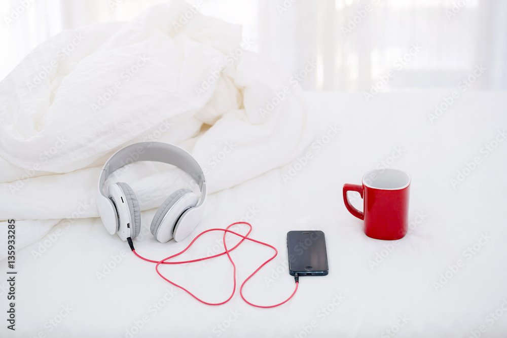 Classic Ukulele guitar on bed with smart phone and coffee cup