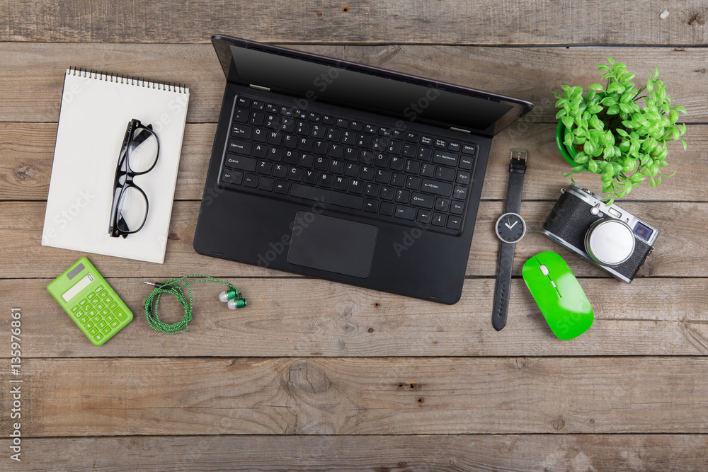 Workplace from above - laptop, notepad, glasses and camera on the wooden desk