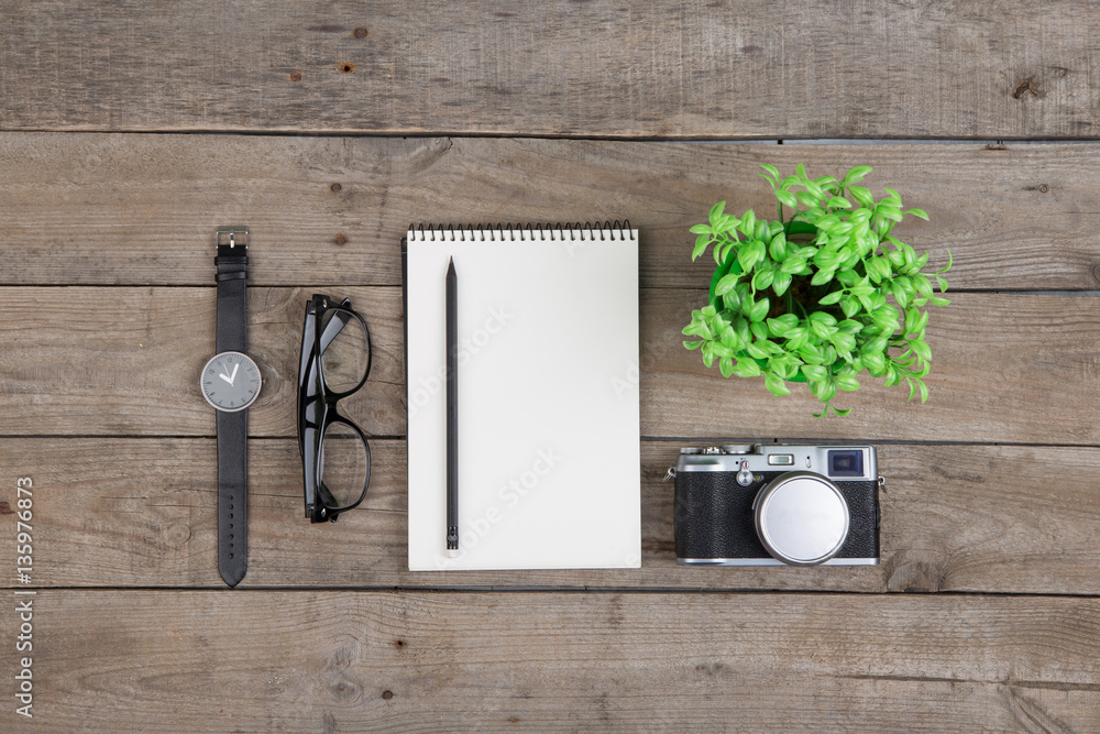 Notepad, glasses and camera on the wooden desk