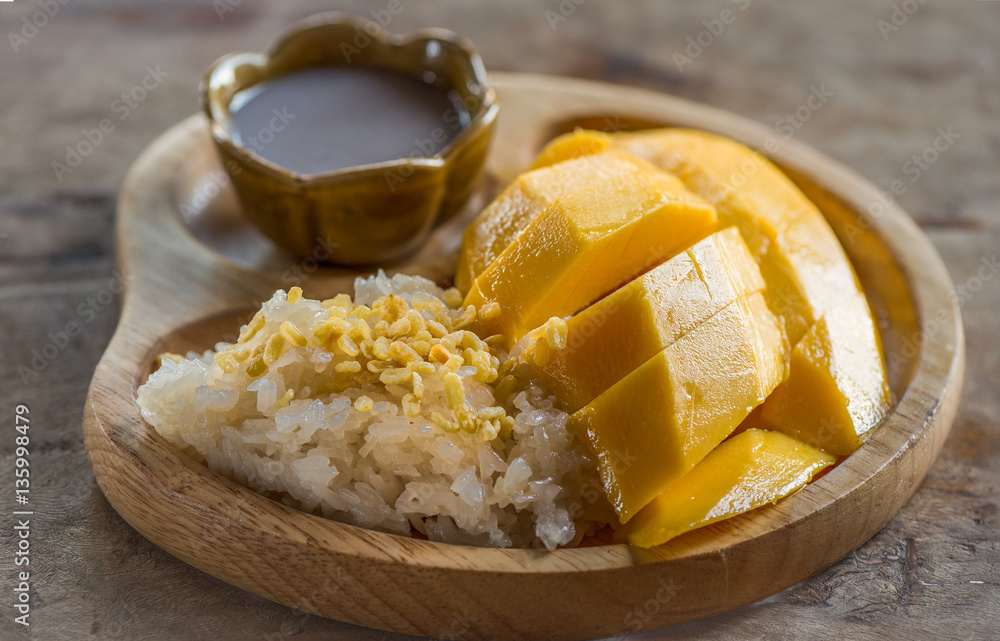 Mango sticky rice with coconut milk on the wooden table backgrou