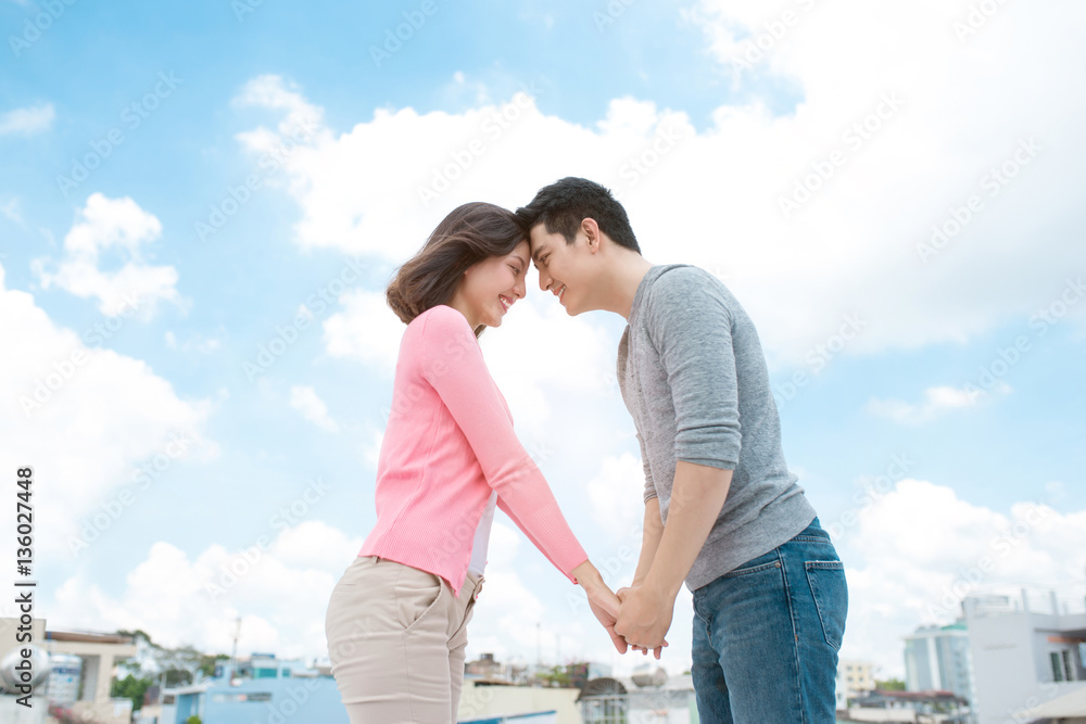 Young beautiful woman and asian man laugh against the dark blue