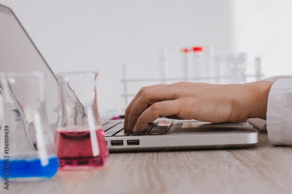 Scientist typing documents into laptop in the laboratory