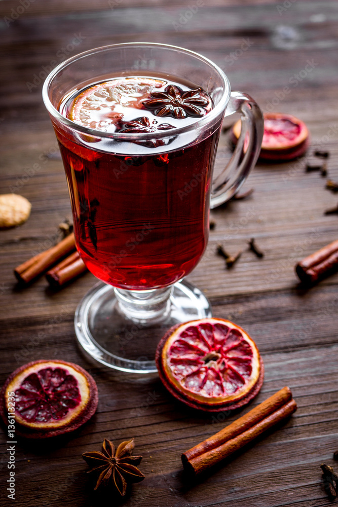 mulled wine with spices in cup on wooden background