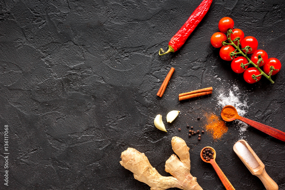 spices in wooden spoon on dark background top view