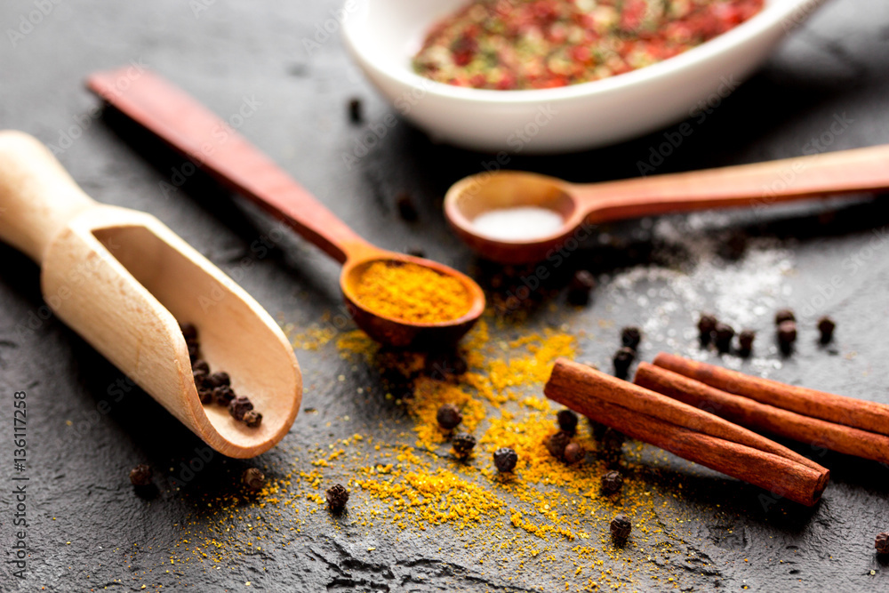 spices in wooden spoon on dark background