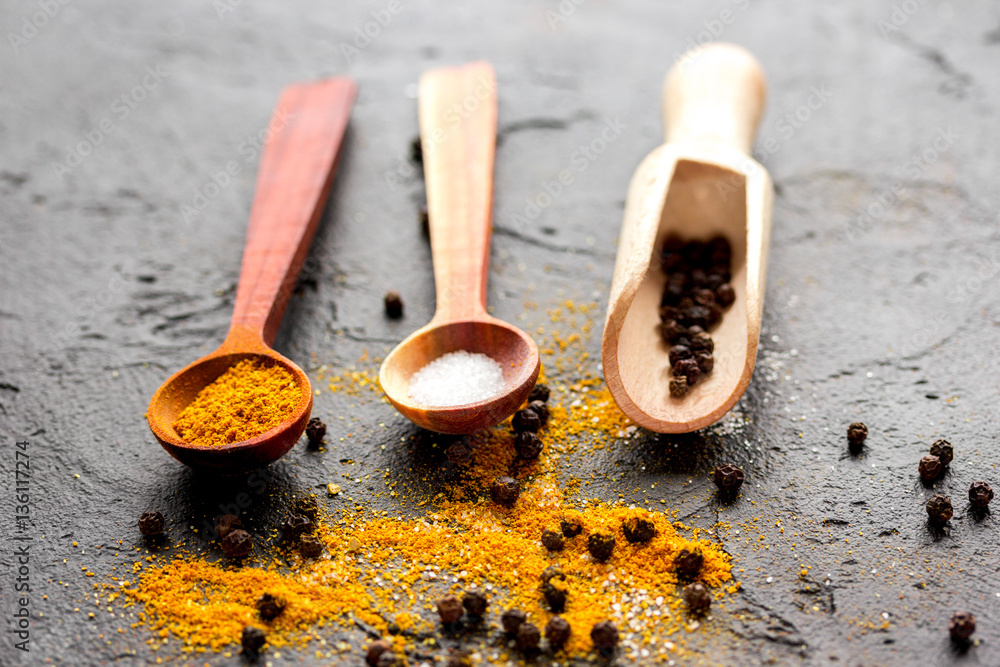 spices in wooden spoon on dark background