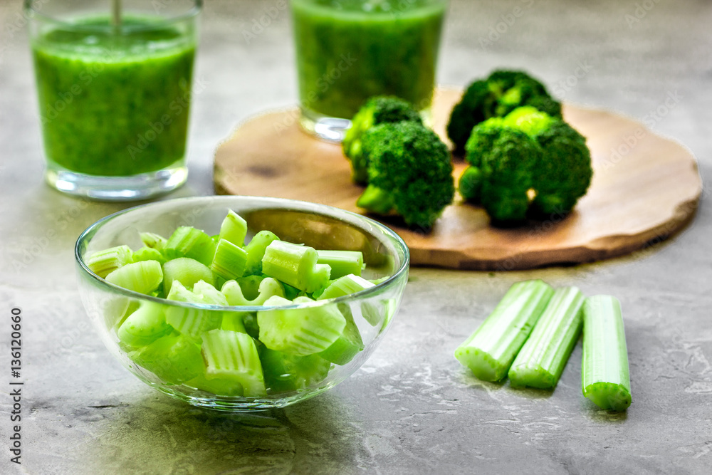 Green vegetable smoothie in glass at gray background