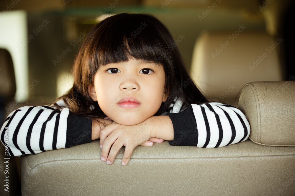 Portrait kid sitting in the car looking out windows, ready for vacation trip