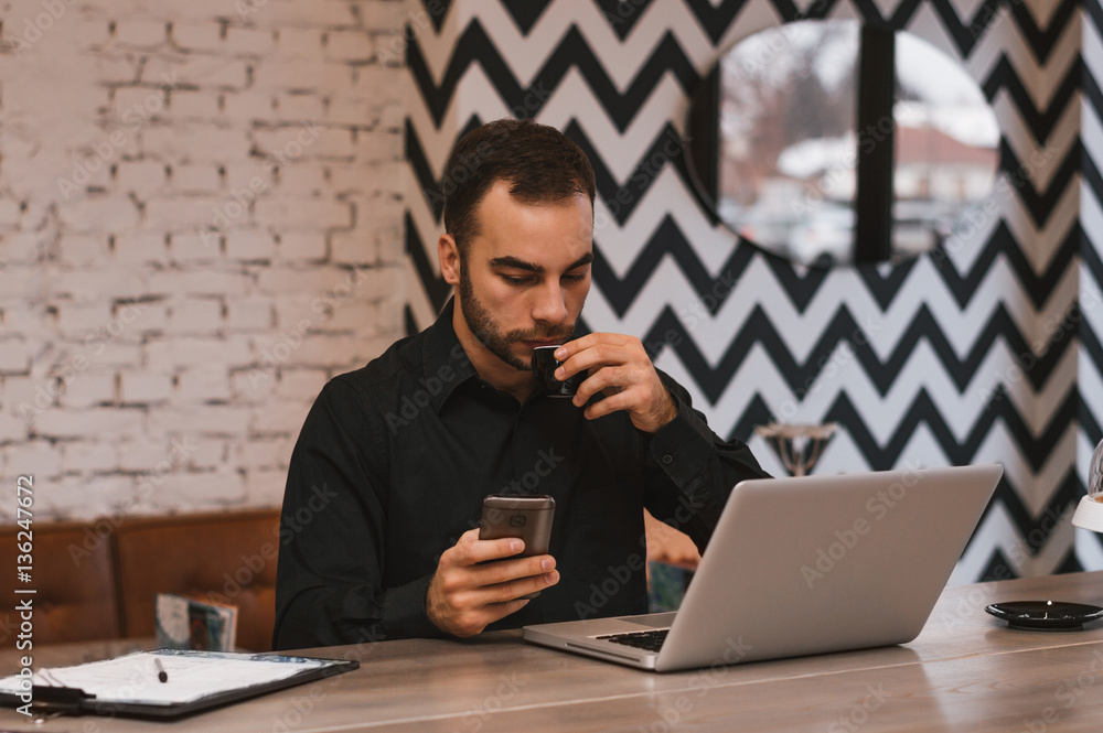 Businessman drinking a coffee and looking in phone in restaurant