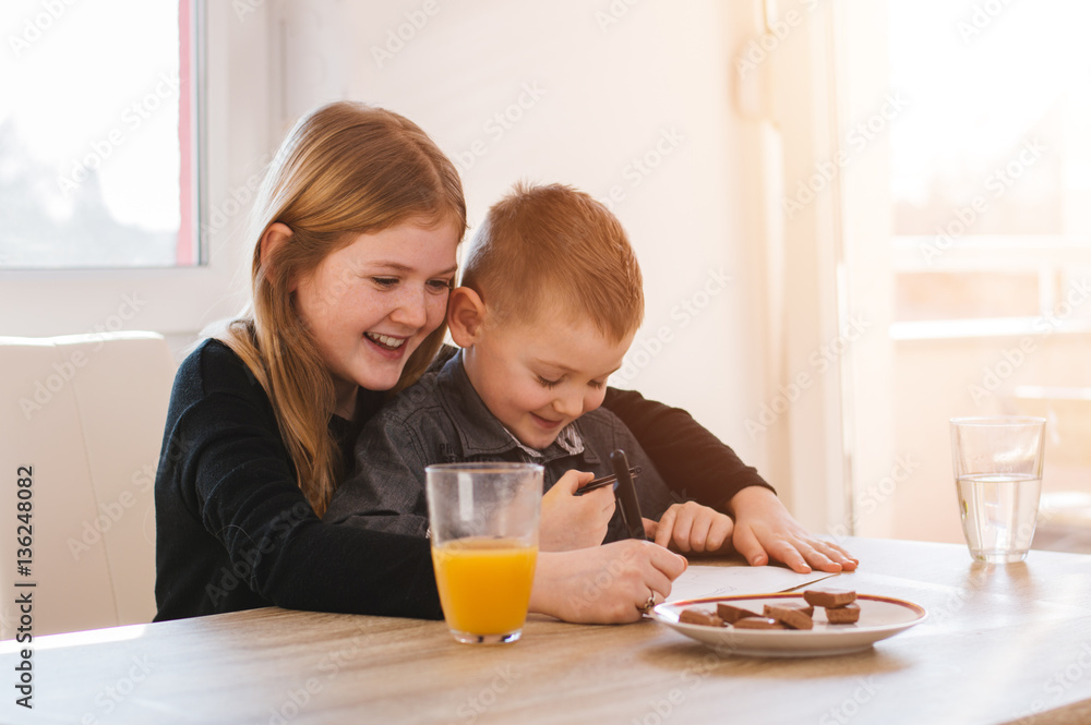 Happy little girl and her brother writting on paper. Lens flare