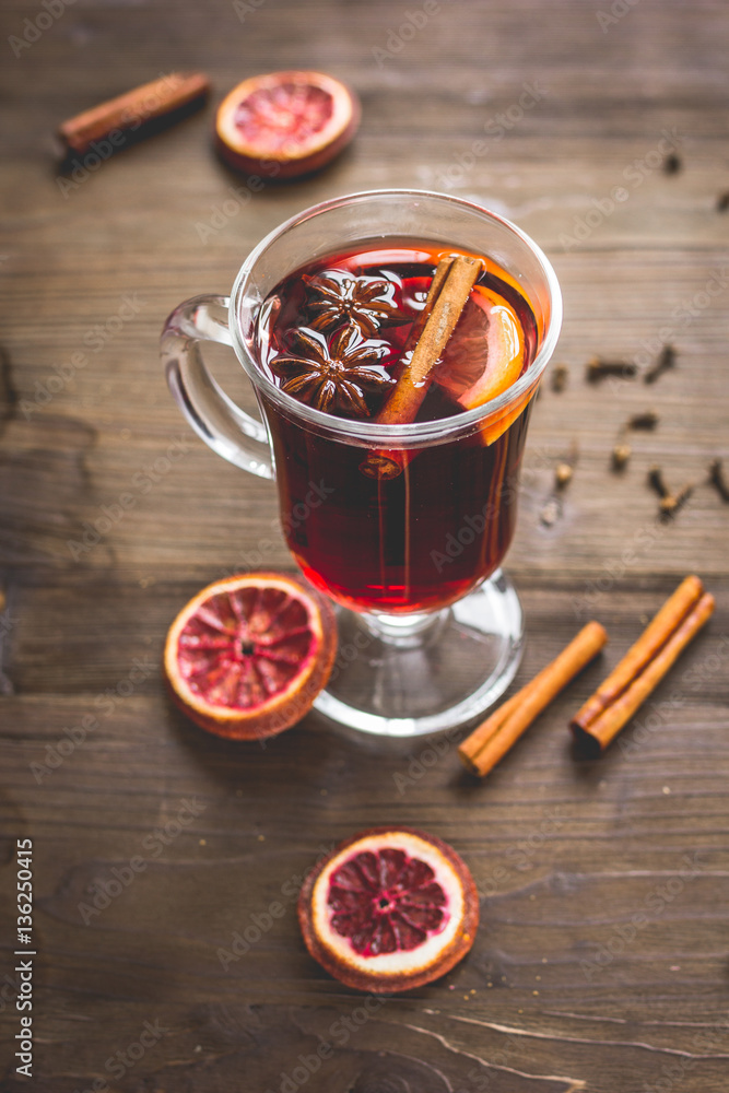 mulled wine with spices in cup on wooden background