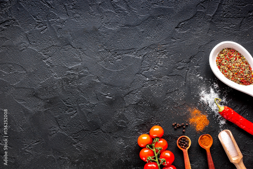 spices in wooden spoon on dark background top view