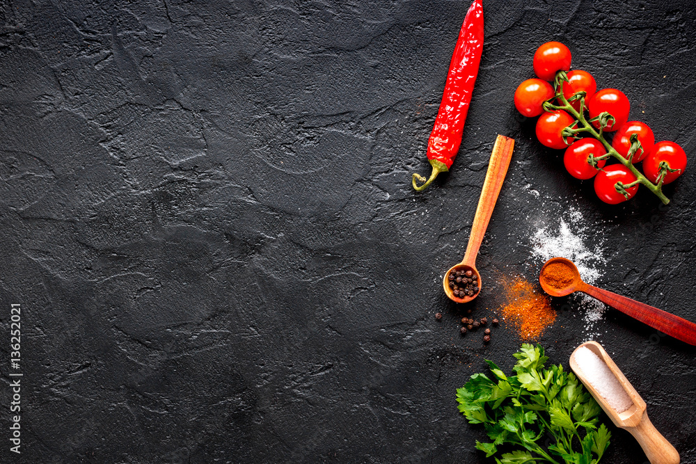 spices in wooden spoon on dark background top view