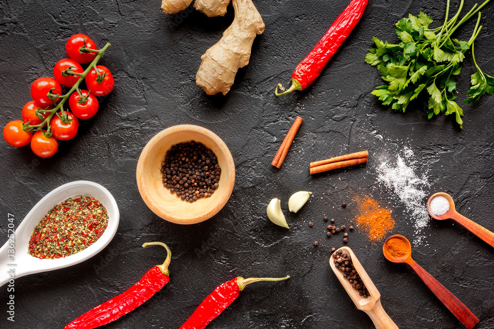 spices in wooden spoon on dark background top view