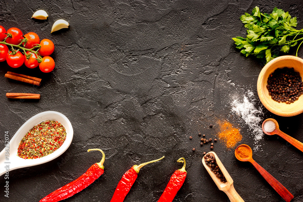 spices in wooden spoon on dark background top view