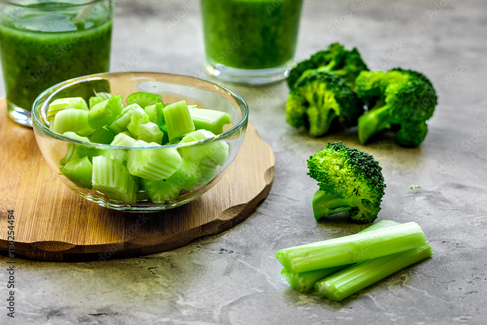 Green vegetable smoothie in glass at gray background