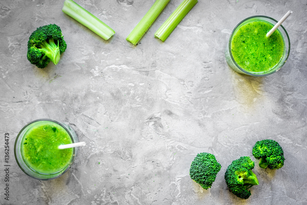 Green vegetable smoothie in glass at gray background top view