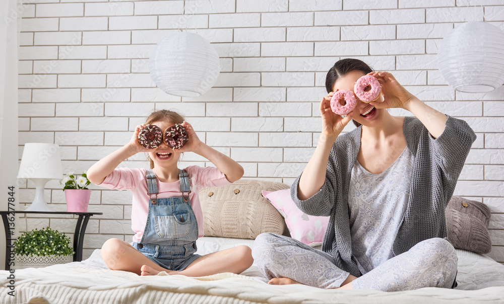 Mother and her daughter eating donuts