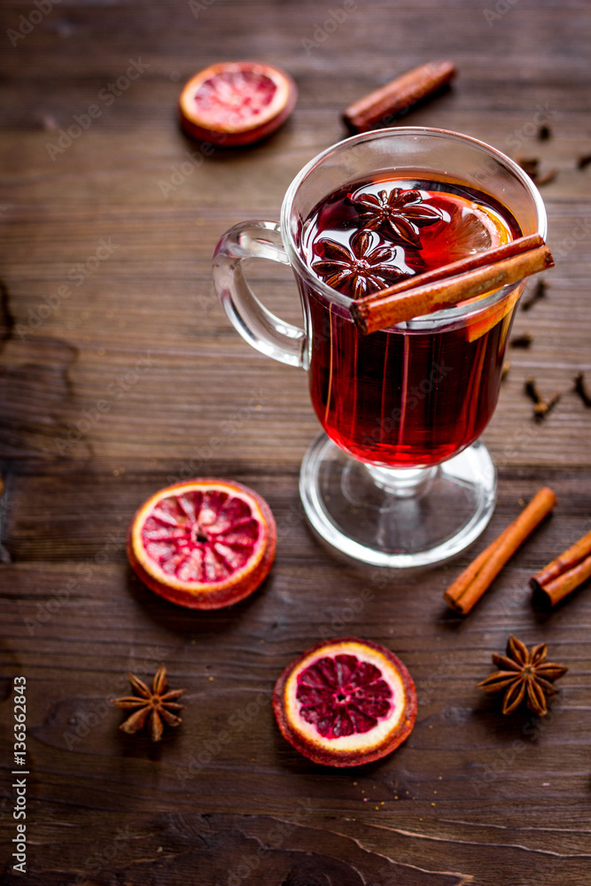 mulled wine with spices in cup on wooden background