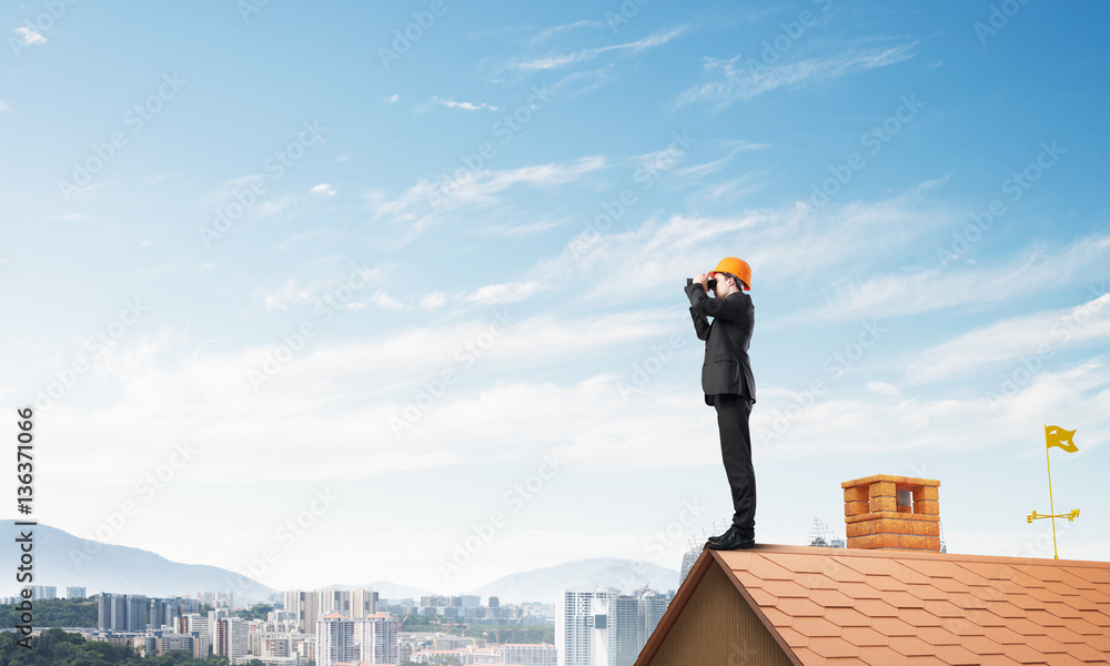 Engineer man standing on roof and looking in binoculars. Mixed media