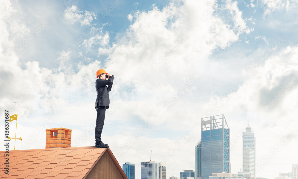 Engineer man standing on roof and looking in binoculars. Mixed m