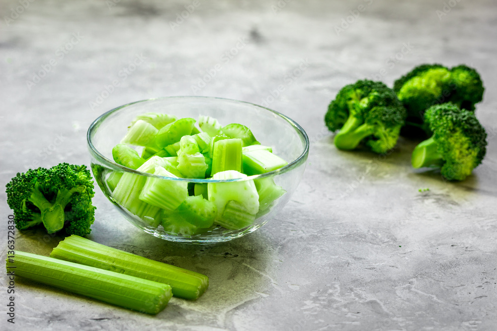 Green vegetable smoothie in glass at gray background