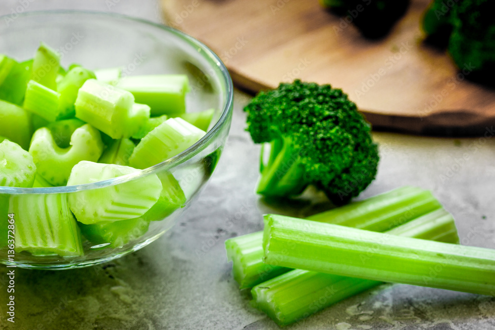 Green vegetable smoothie in glass at gray background