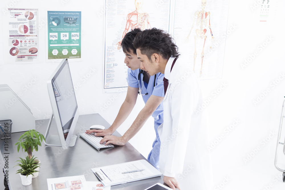 Two doctors are talking while watching a personal computer