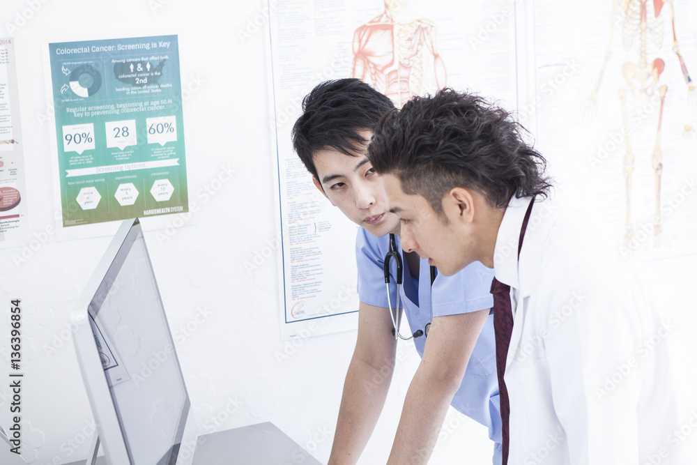 Two doctors are talking while watching a personal computer