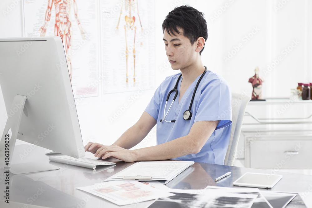 A young male doctor is using a personal computer