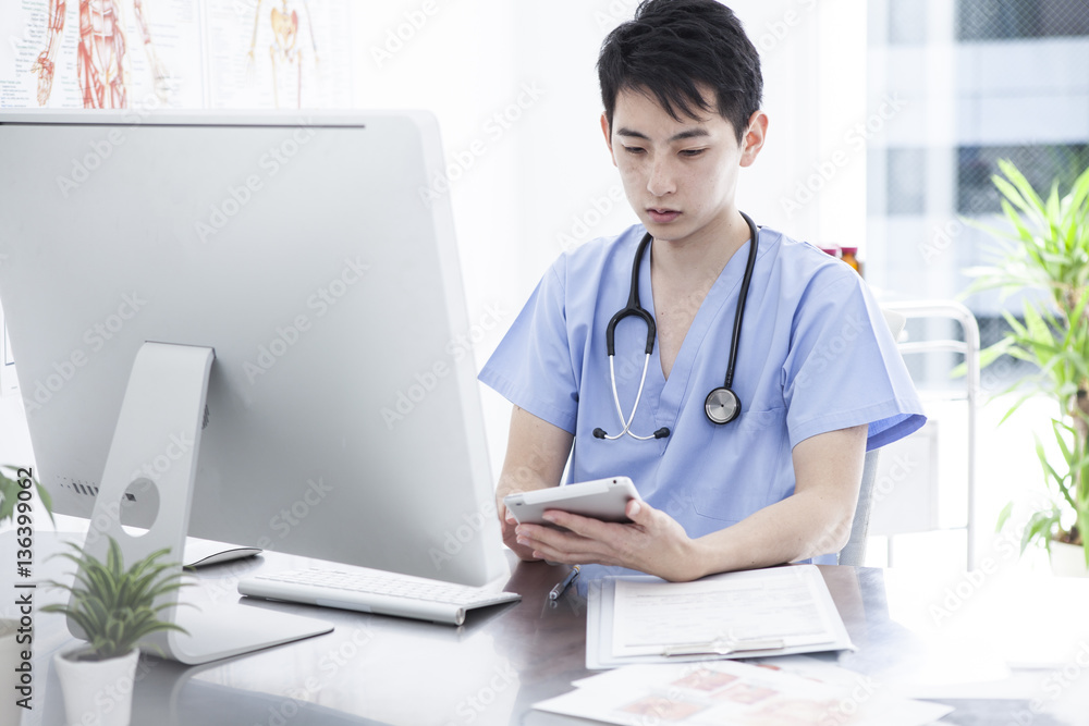 A young male doctor is watching the tablet