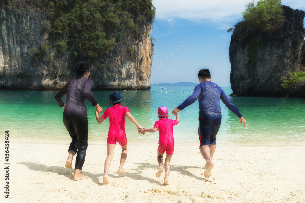 年夏天亚洲幸福家庭在海滩上奔跑的照片