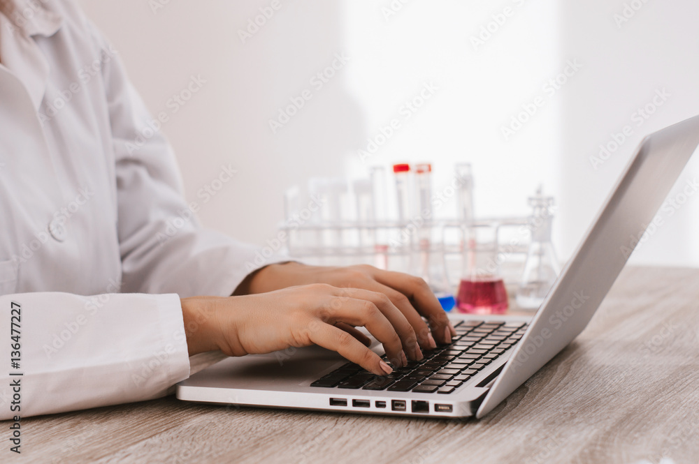 Scientist typing documents into laptop in the laboratory.