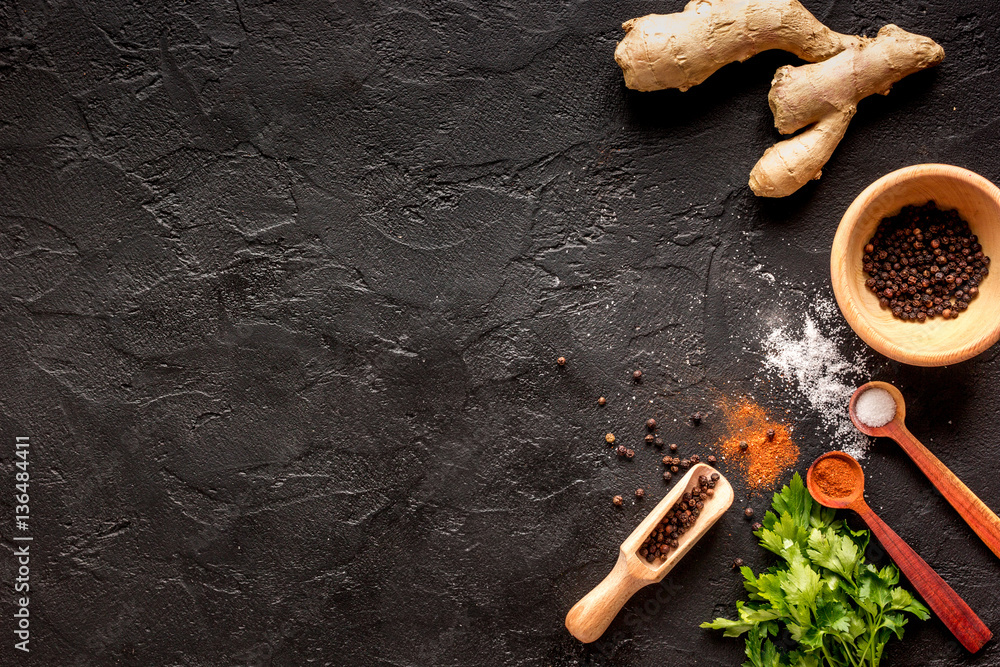 spices in wooden spoon on dark background top view