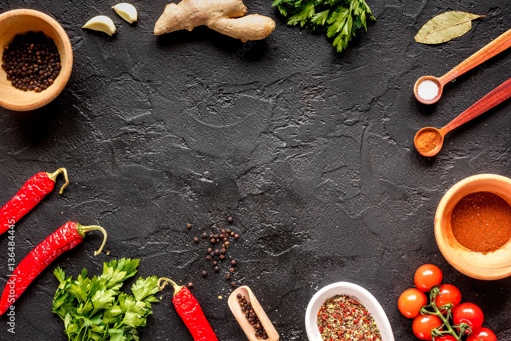 spices in wooden spoon on dark background top view