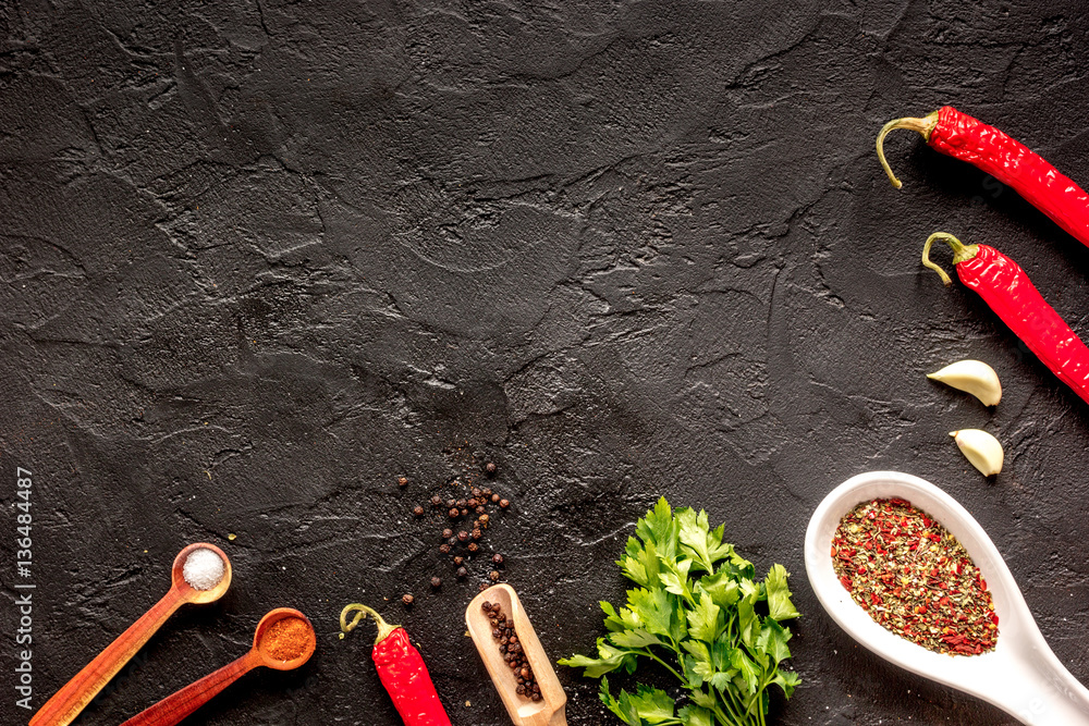 spices in wooden spoon on dark background top view